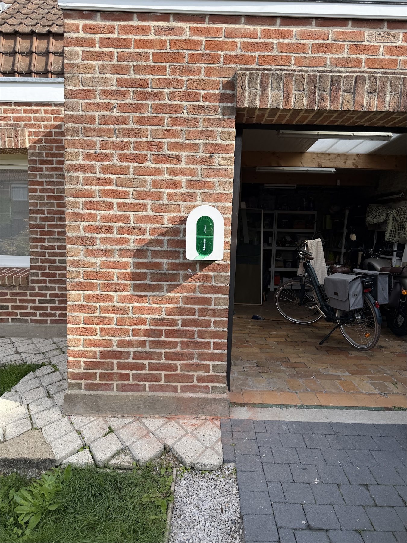 Borne Schneider Charge installée sur le mur en briques près d’un garage